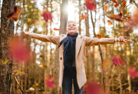 Mature woman in autumn forest, dressed in cozy fall attire, Reflection and connection with nature,...
