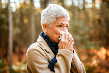 Woman coughing and blowing her nose in autumn. Cold and fluの写真素材