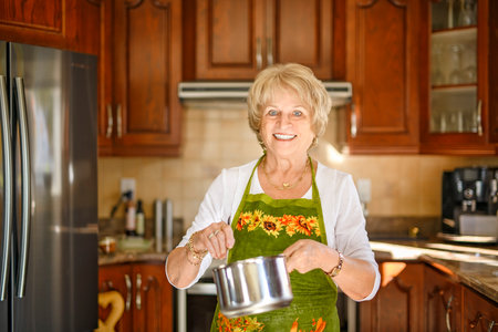 Happy senior woman preparing lunch in modern kitchen cooking for the family at homeの写真素材