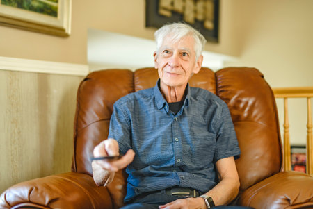 Portrait of retired senior man standing at home watching tvの写真素材