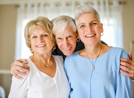 Happy daughter embracing her two elderly parents at living room.の写真素材