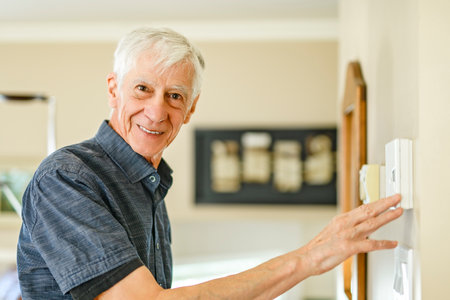 Senior Man using Heating Thermostat At Home In Energy Crisisの写真素材