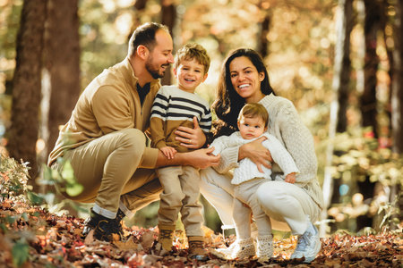 Beautiful young family on a walk in autumn forestの写真素材