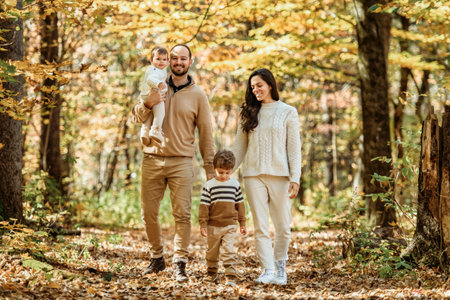 Beautiful young family on a walk in autumn forestの写真素材