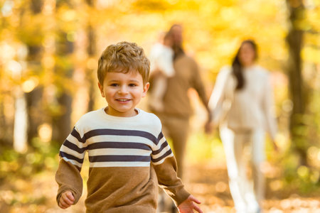 Beautiful young family on a walk in autumn forestの写真素材