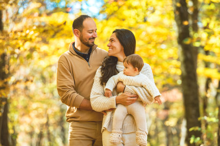 Beautiful young family on a walk in autumn forest with babyの写真素材