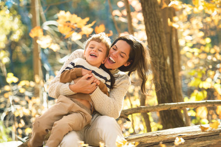 young mother with son in autumn in beautiful forestの写真素材