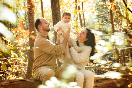 Beautiful young family on a walk in autumn forest with babyの写真素材