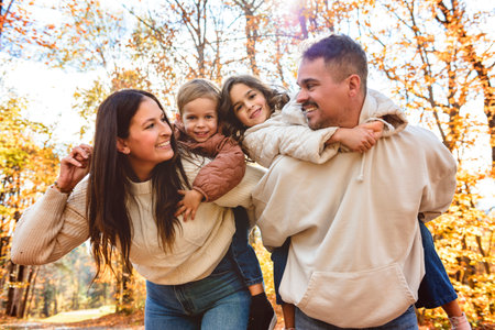 Beautiful young family having great time in autumn forestの写真素材