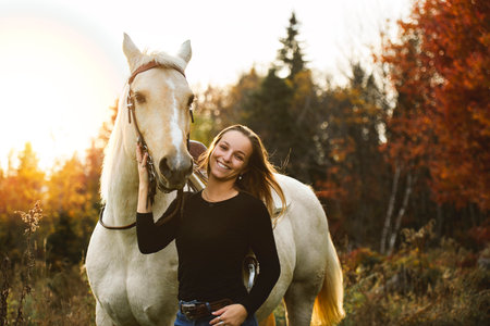 Young woman having great time with a horse in field on autumn season. sunset hourの写真素材