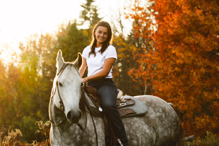 Young woman having great time with a horse in field on autumn season. sunset hourの写真素材