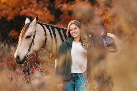 Young woman having great time with a horse in field on autumn season. sunset hourの写真素材