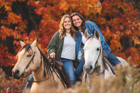 Two Young womans having great time with horse in field on autumn season. sunset hourの写真素材