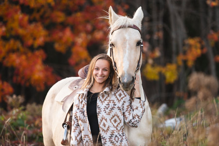 Young woman having great time with a horse in field on autumn season. sunset hourの写真素材