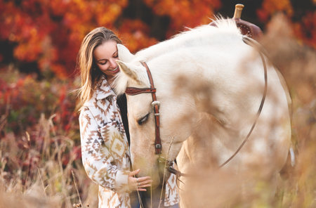 Young woman having great time with a horse in field on autumn season. sunset hourの写真素材