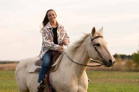 Young woman having great time with a horse in field on autumn season. sunset hour