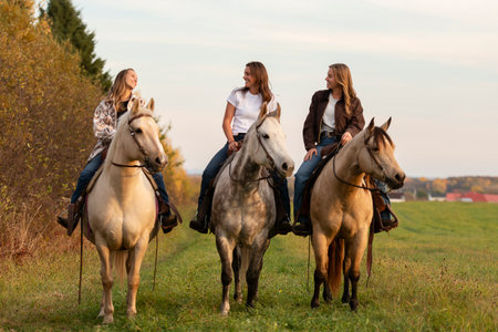 Three Young woman having great time with horse in field on autumn season. sunset hourの写真素材