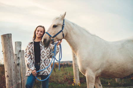 Young woman having great time with a horse in field on autumn season. sunset hourの写真素材