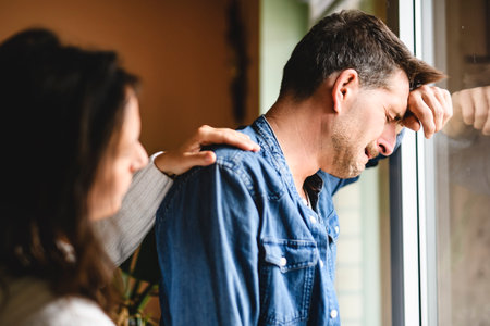 couple enjoying quiet time close to a window. The man crying and women consolingの写真素材