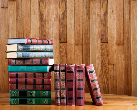 Richly decorated volumes of books with a gold lettering on the beautiful wooden shelfの写真素材