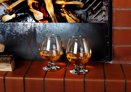 Two tanks of cognac on the old brick fireplace with a bright fire