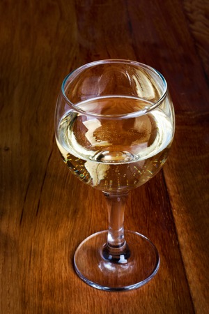 A glass of white wine on wooden old counter topの写真素材