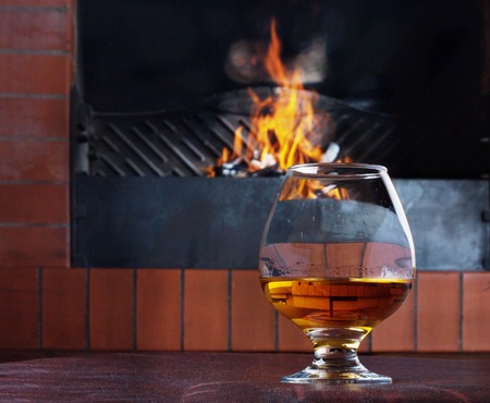 Two glasses of cognac on the old brick fireplace with a bright fireの写真素材