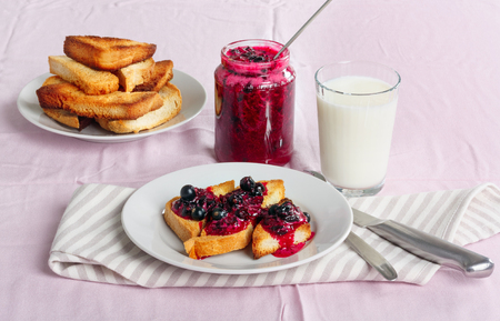 Delicious toasts bread with homemade currant jam with milk on bright crimson tableclothの写真素材