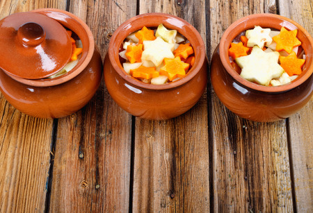 Traditional rustic home vegetable stew in three clay pots on old vintage wooden table. Top view flat lay group objectsの写真素材