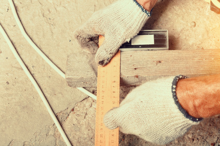 The worker measures the distance with the ruler on wooden board for workの写真素材