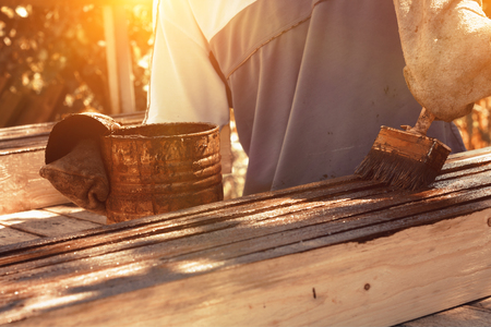 Male worker in old glove is painting the fence boards in outdoorの写真素材