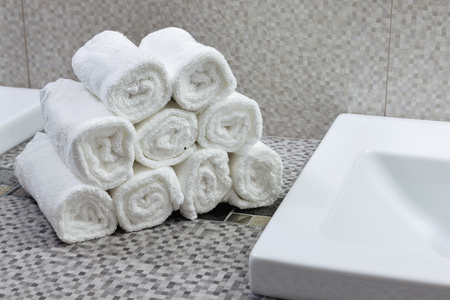 Stack of clean white towels on ceramic countertop in modern bathroomの写真素材