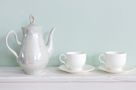 Set of tea cups and  ceramic teapot  on wooden shelfの写真素材