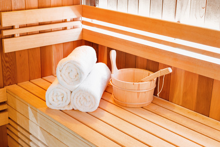Traditional wooden sauna for relaxation with bucket of water and set of clean towels