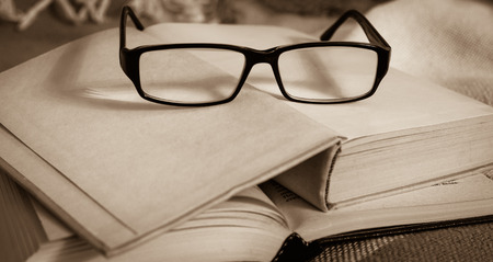 Stack of open vintage books with glasses on  table
