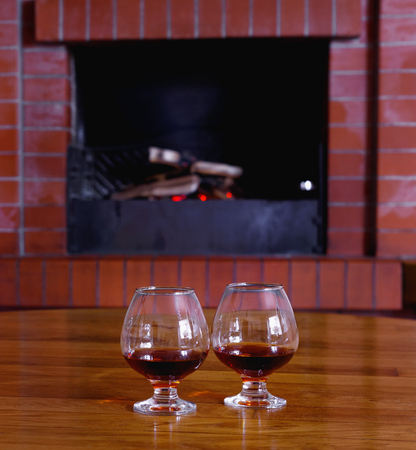 Two tanks of cognac on background of old brick fireplace with  bright fireの写真素材
