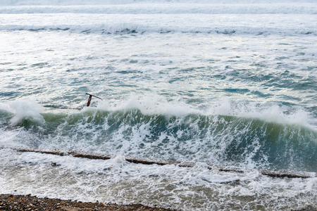 Big sea waves breaking on concrete pier in windy weather. Weather elements on background of blue sky and white cloudsの写真素材
