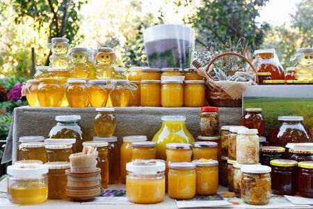  Assortment of honey jars at market stall. Sale of natural honey in fair outdoor. Production of honey.の写真素材