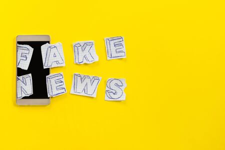 Paper art banner on yellow backdrop in style zine wiht words fake news. Social media concept. Paper letters on smartphone: fake newの写真素材