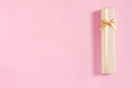 Golden gift boxes with bow for congratulations on pink paper background. Top view, flat lay, copy space concept.の写真素材