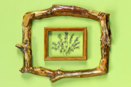Wooden frames with  bouquet of fragrant lavender in  rustic style on green wall. Holiday party decoration. Vintage floral card. Interior concept.の写真素材