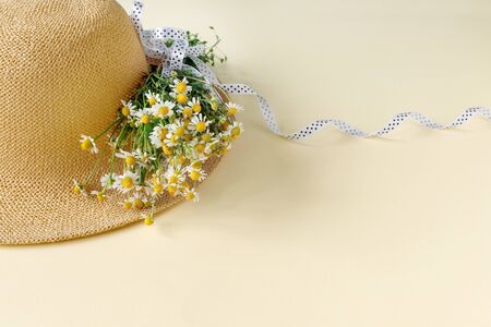 Beautiful straw hat with  bouquet of daisies on sand sunny day. Nature summer background. 
Creative greeting cardの写真素材