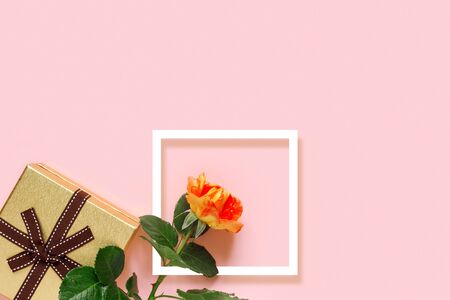 Beautiful yellow roses with golden gift box and bow on delicate pink paper background. Birthday card. 
Flat lay, top view, copy space concept.の写真素材