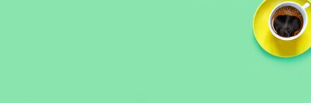 Cup of aromatic hot coffee with foam and steam on green paper background. Copy space for your text.
 Flat lay, top view, copy space concept.
の写真素材