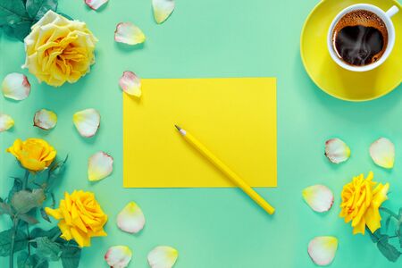 Bouquet of beautiful yellow roses and cup of hot fresh aromatic coffee on  green paper background. Notebook sheet  and  pencil for your text.
Flat lay, top view, copy space concept.の写真素材
