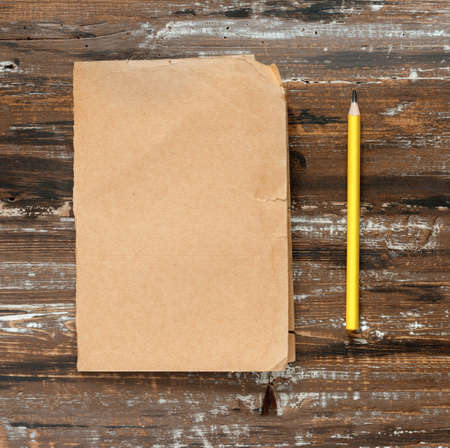 Pencil and sheet of yellow paper for text on wooden background. Flat lay, top view, copy space concept.の写真素材