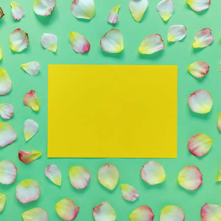 Beautiful rectangular pattern of pink and yellow rose petals and leaves on green paper background....