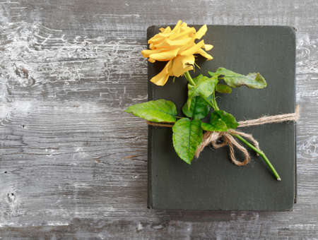 Bouquet of beautiful yellow roses and stack of old vintage books on wooden background....