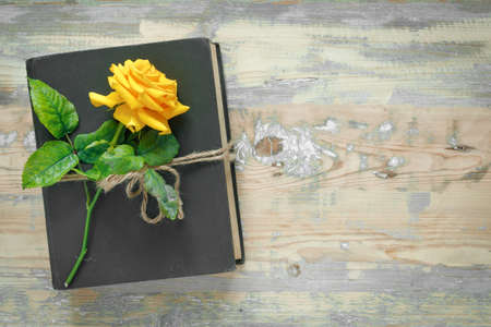 Bouquet of beautiful yellow roses and stack of old vintage books on wooden background. Copy space for nostalgic inscription. Flat lay, top view, copy space concept.の写真素材