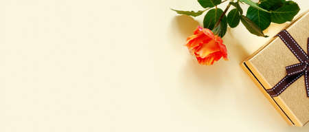 Beautiful yellow roses with golden gift box and bow on delicate yellow paper background. Wedding invitation card. With place for your text. Flat lay, top view, copy space concept.の写真素材